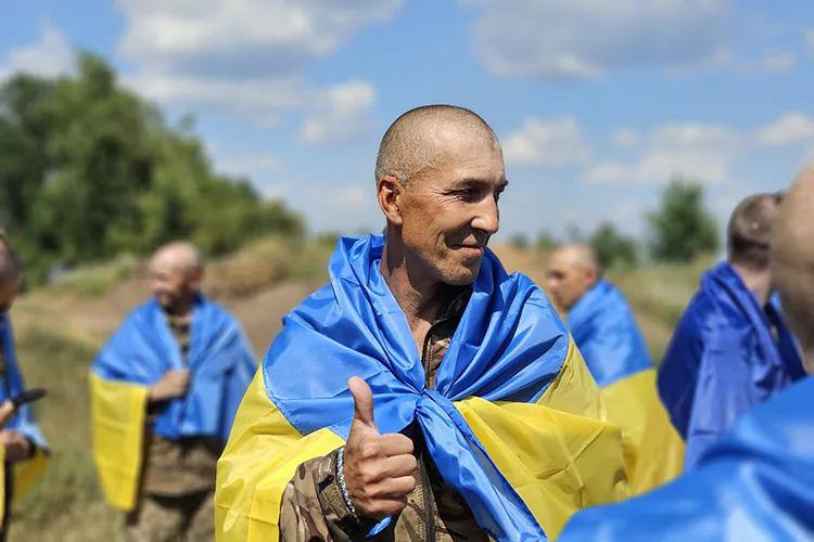 Un soldado envuelto con la bandera de Ucrania, que regresa a casa después de permanecer cautivo en Rusia